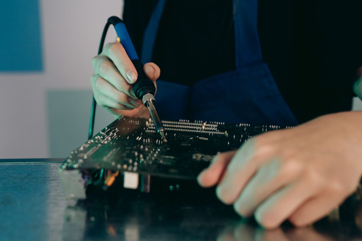 Hands soldering electronic components on a printed circuit board
